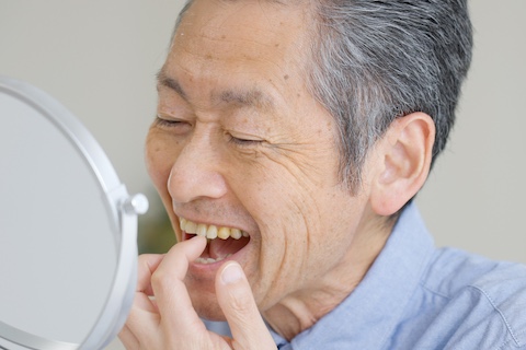 手鏡で歯を見る男性