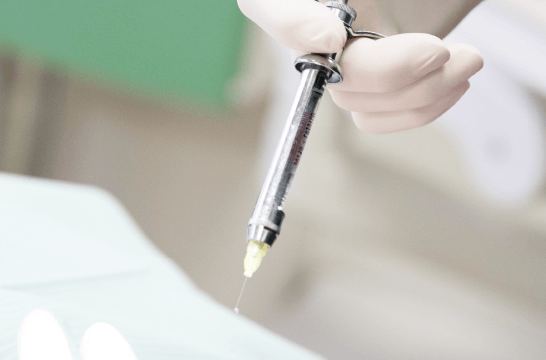 駐車器を持つグローブをした歯科医師の手の写真。